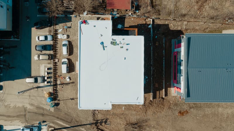 Aerial view of an apartment building with flat roof in construction ballasted system with geotextile PVC or EPDM membrane - Oak Grove Roofing