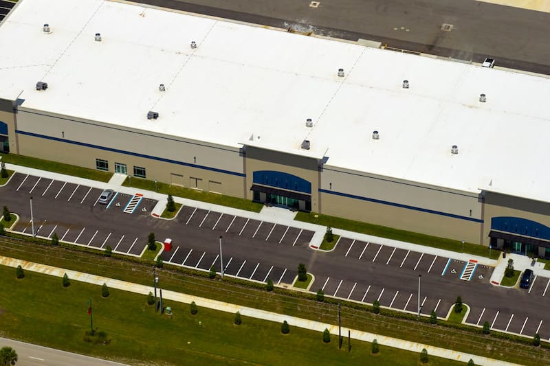 Aerial view of industrial park with goods warehouses and logistics centers in city zone from above - Oak Grove Roofing