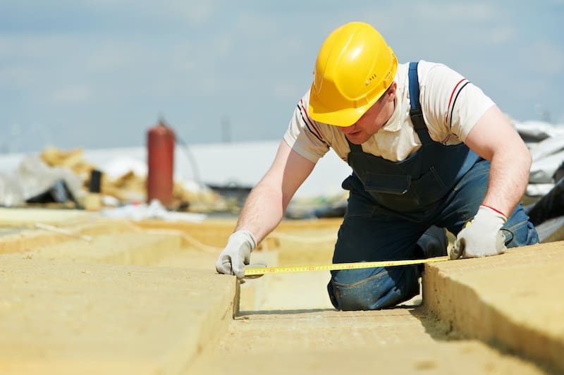 roofer worker measuring insulation material - Oak Grove Roofing