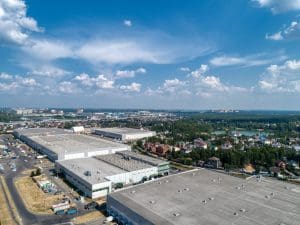 Huge warehouse building with flat roof and cars near city - Oak Grove Roofing - Oak Grove Roofing